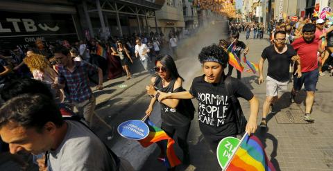 Activistas del colectivo LGTB huyen de una tanqueta policial que ha disparado un cañón de agua contra ellos este domingo en Estambul, Turquía