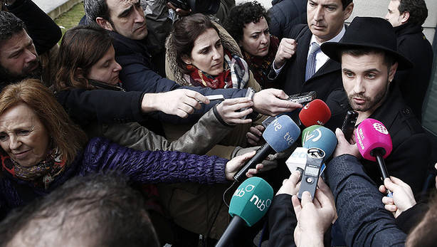 El artista Abel Azcona (d) atiende a los medios a su salida del Palacio de Justicia de Pamplona junto a su abogado Jorge Morales (2d) tras declarar como investigado