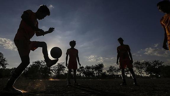 Un grupo de niños juega con una pelota en la calle