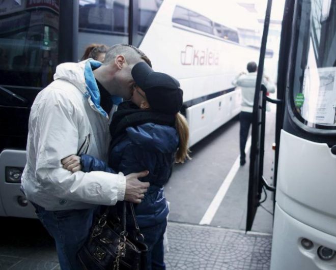Una pareja se besa en una estación de autobuses