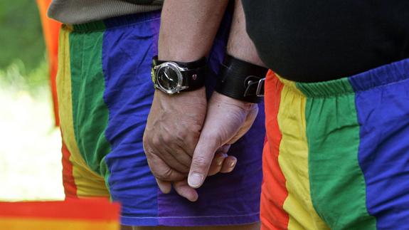 Una pareja se da la mano mientras participa en una marcha con motivo del día internacional del orgullo gay